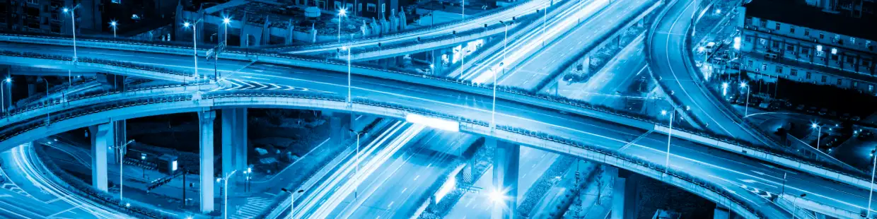 都市の夜景に広がる高速道路網の構成を表現した画像。上下複数層に分かれた高架道路が複雑に交差し、立体的に都市空間を横断している。長時間露光による車両の光跡が道路を流れる交通のスピード感と動きを視覚的に示し、都市インフラの機能性やモビリティの高度化を象徴している。