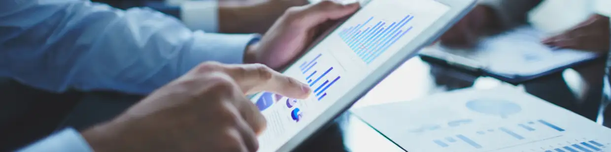 ビジネスシーンにおいてタブレット端末上の棒グラフや円グラフを分析している様子。データの可視化や意思決定支援を目的とした地理情報の活用を示す図。